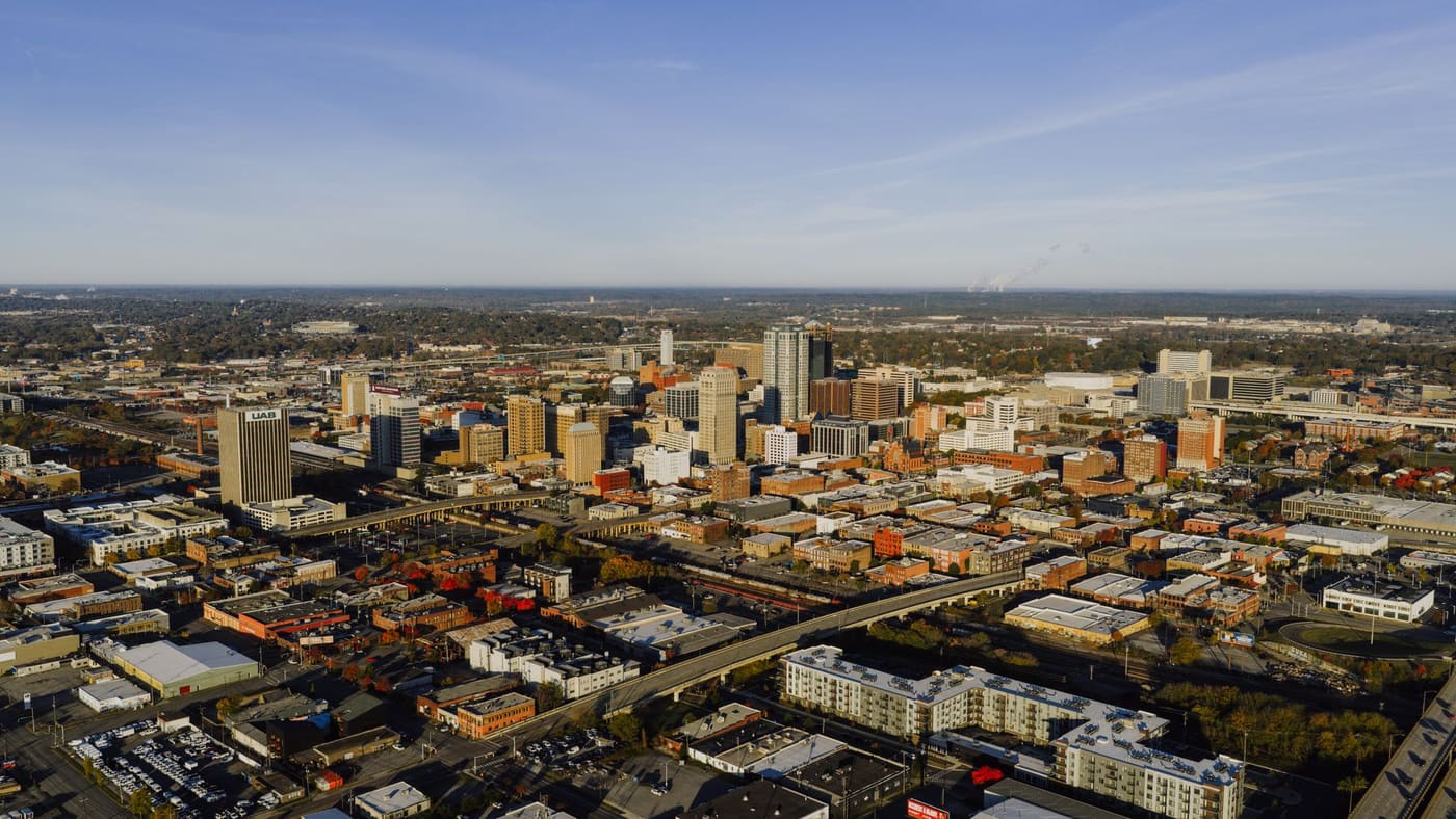 Aerial view of downtown Birmingham, Alabama, with the UAB tower on the left and autumn trees across the city
