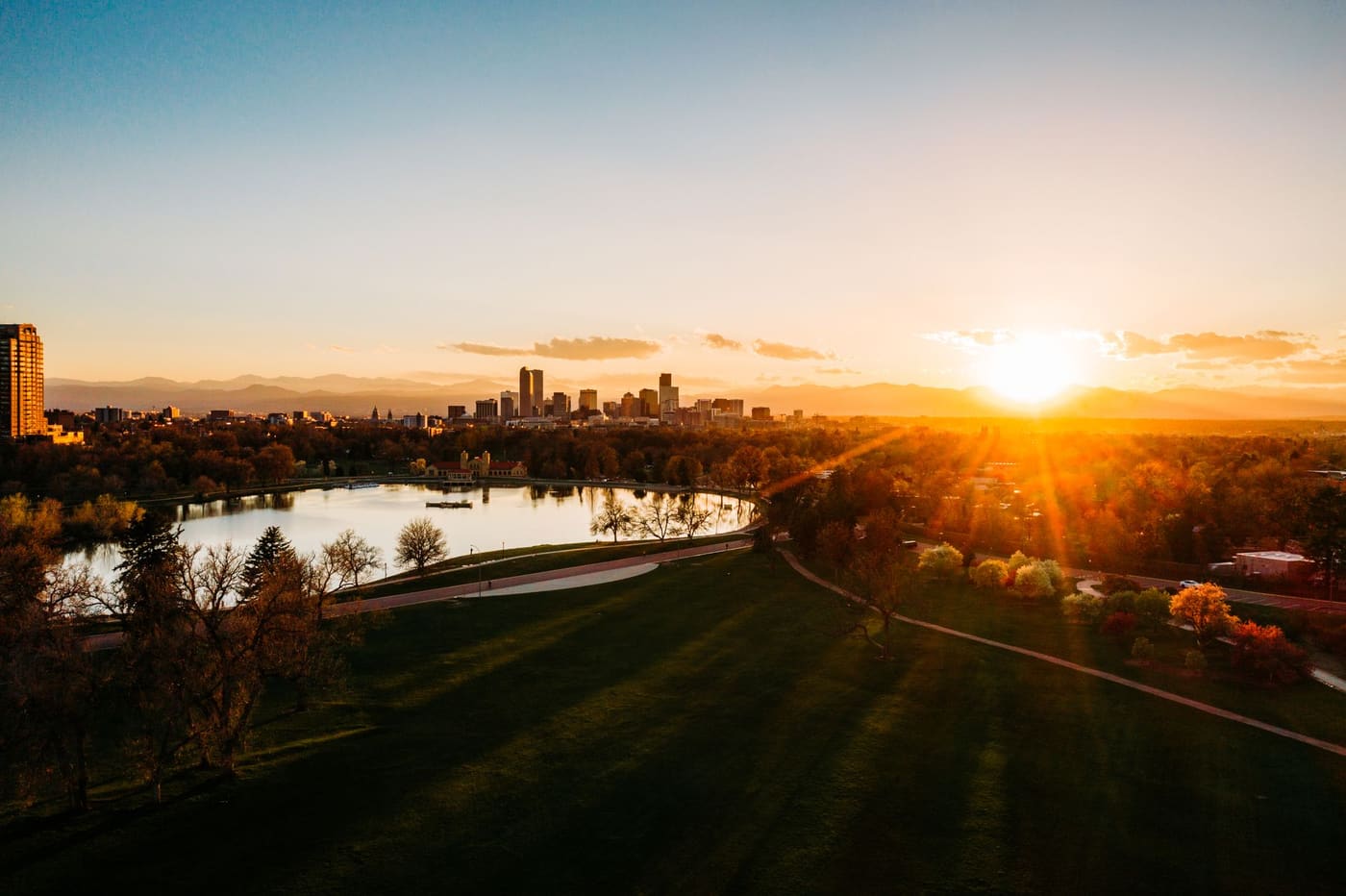 Sunset over City Park and Ferril Lake in Denver, with the downtown skyline and the Front Range behind it